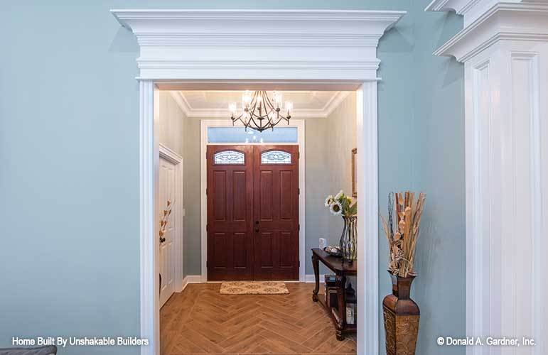 Foyer with herringbone wood flooring and a double front door topped with a transom.