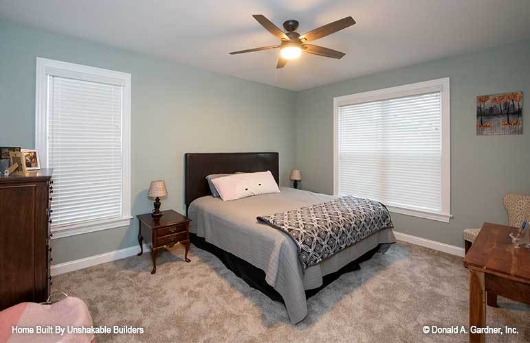 This bedroom is furnished with a dark wood bed, matching nightstands, a wooden dresser, and a desk.