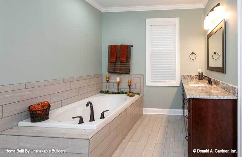 The primary bathroom includes a deep soaking tub with wrought iron fixtures and tile surround.