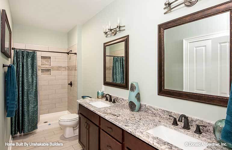 Another bathroom with a tub and shower combo, a toilet, and double sink vanity paired with framed mirrors.