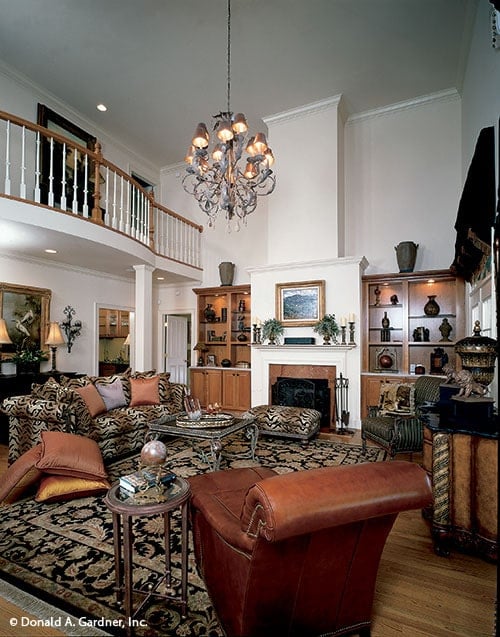 The living room includes a leather chaise lounge and a fireplace flanked by wooden built-ins.