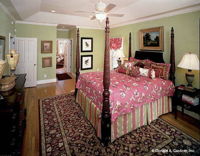 Primary bedroom with a coved ceiling, green walls, and a four-poster bed over a patterned area rug.