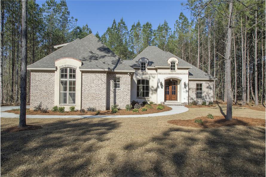 Front exterior view showing the brick cladding, hipped rooflines, arched dormers, and a portico.