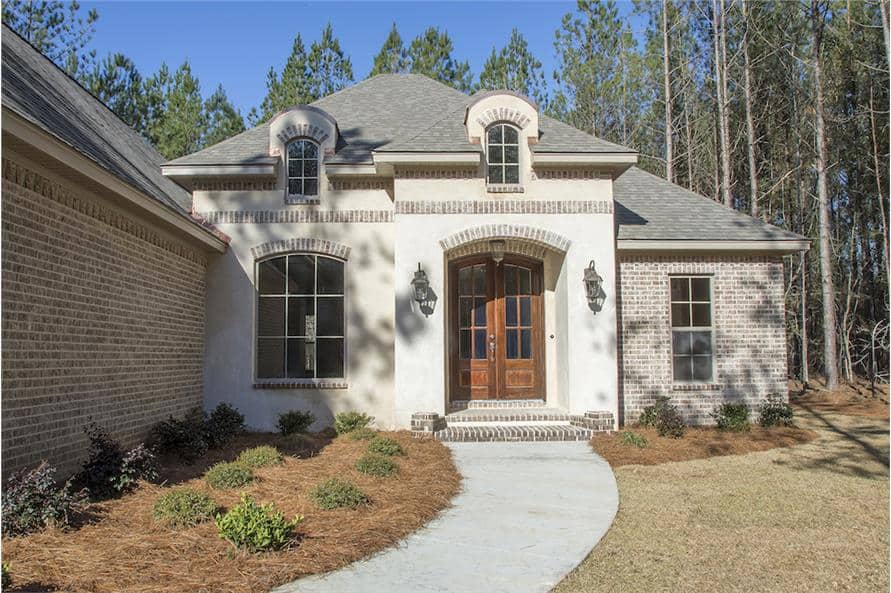 A closer look at the arched entry graced with brick accents and stoop.