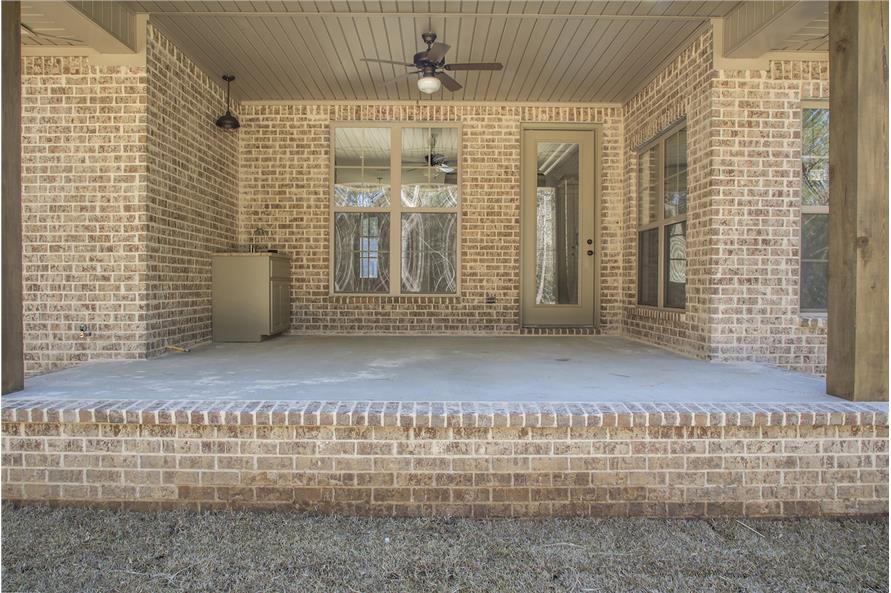 Rear covered porch with concrete floor and a wood plank ceiling mounted with a fan.