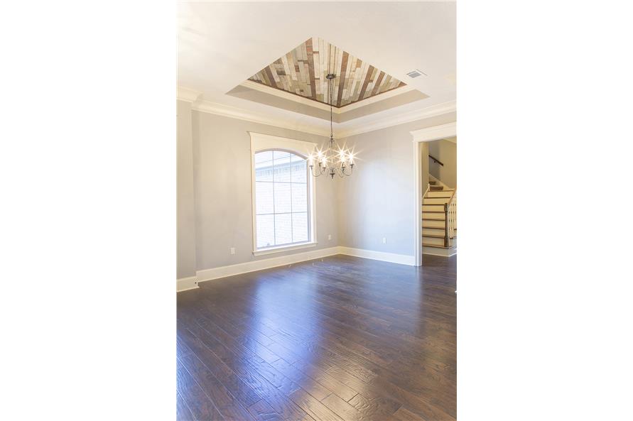 Dining room with a large arched window and a tray ceiling clad in striking wood planks.