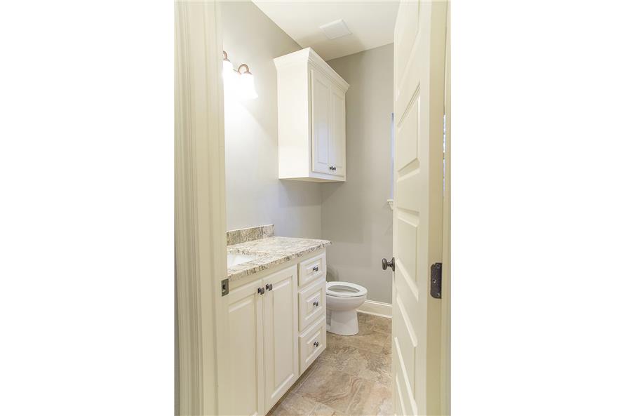 The bathroom offers a sink vanity and a toilet topped with an overhead cabinet.