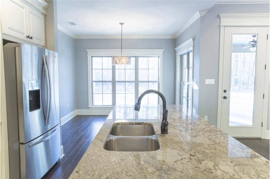 The kitchen island is fitted with a double bowl sink and a gooseneck faucet.