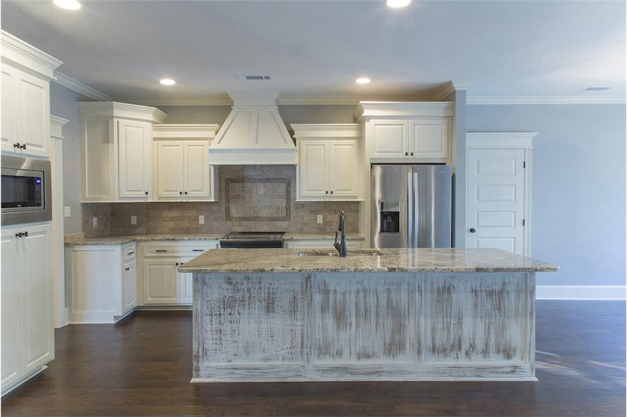 Kitchen with stainless steel appliances, white cabinetry, granite countertops, and a distressed center island.