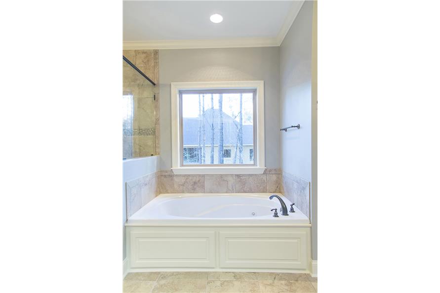 The drop-in bathtub is situated next to the shower and under the picture window.