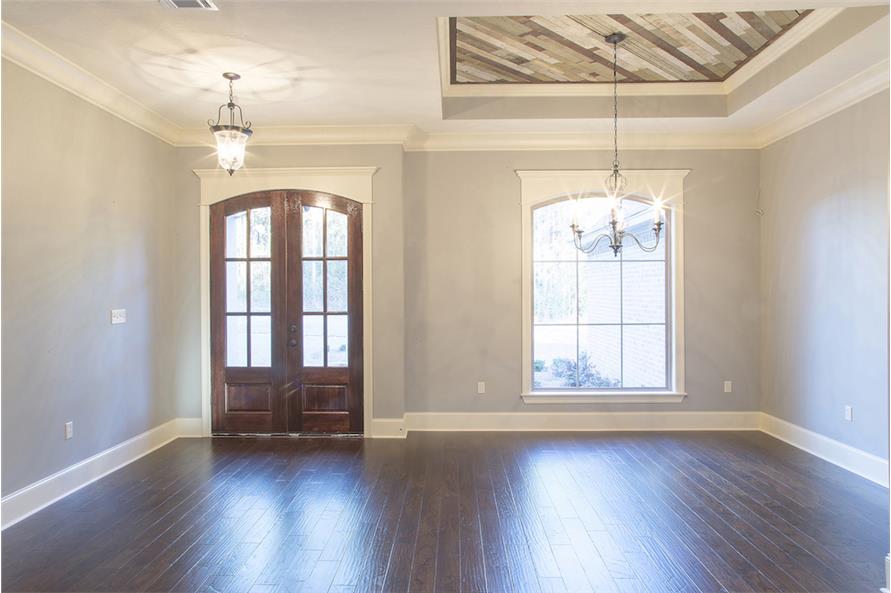 Foyer with an arched french entry door and a glass pendant light. The spare space next to it is dedicated to the dining room.