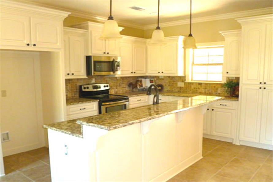 The kitchen is equipped with stainless steel appliances, granite countertops, white cabinetry, and a two-tier island fitted with a sink.