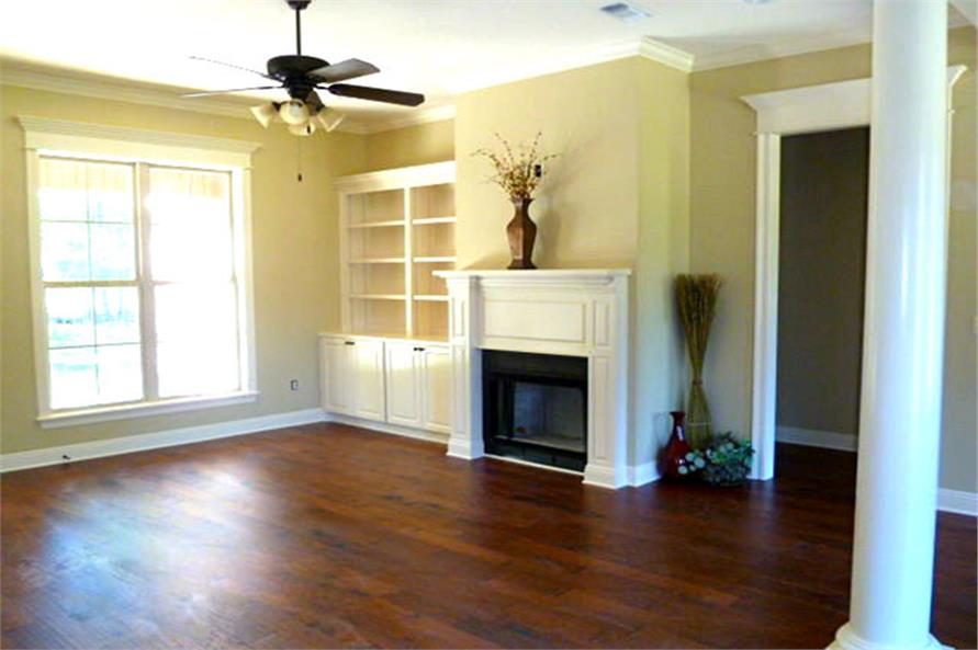 Living room with hardwood flooring, a ceiling fan, and a fireplace fixed next to the white built-in cabinet.