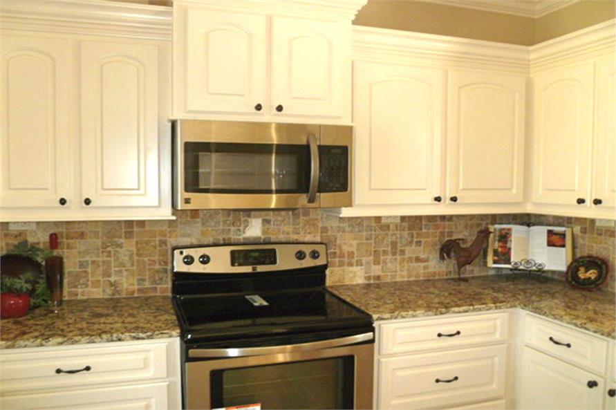 A closer look at the cooking range and oven nestled between the white cabinetry.
