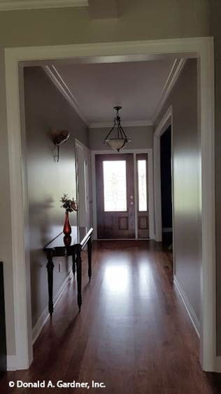 The foyer has a glazed entry door and a dark wood console table topped with a lovely vase.