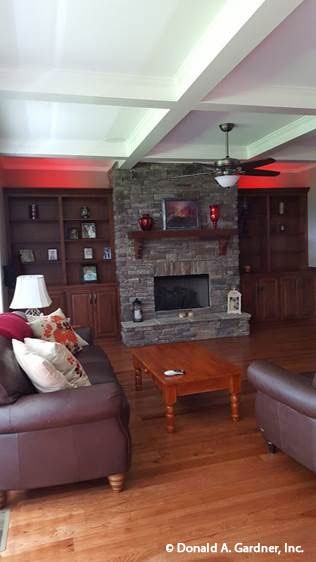 Great room with leather sofas, a wooden coffee table, and a stone fireplace flanked by built-in cabinets.