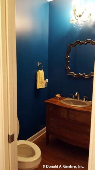 Powder room with a toilet and a sink vanity paired with an intricate mirror.
