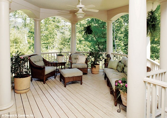 Covered porch with cushioned wicker seats surrounded by decorative archways.