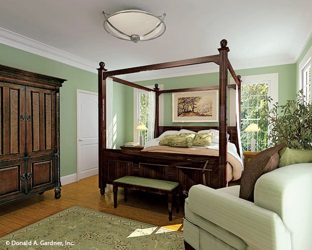 Primary bedroom with a comfy armchair and a canopy bed that matches with the wooden wardrobe.