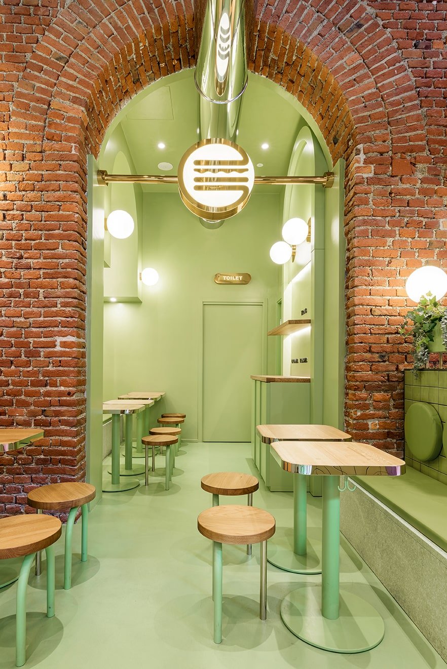 The brick archway leads to a small room fitted with more tables, chairs and a built-in cabinet on the side.