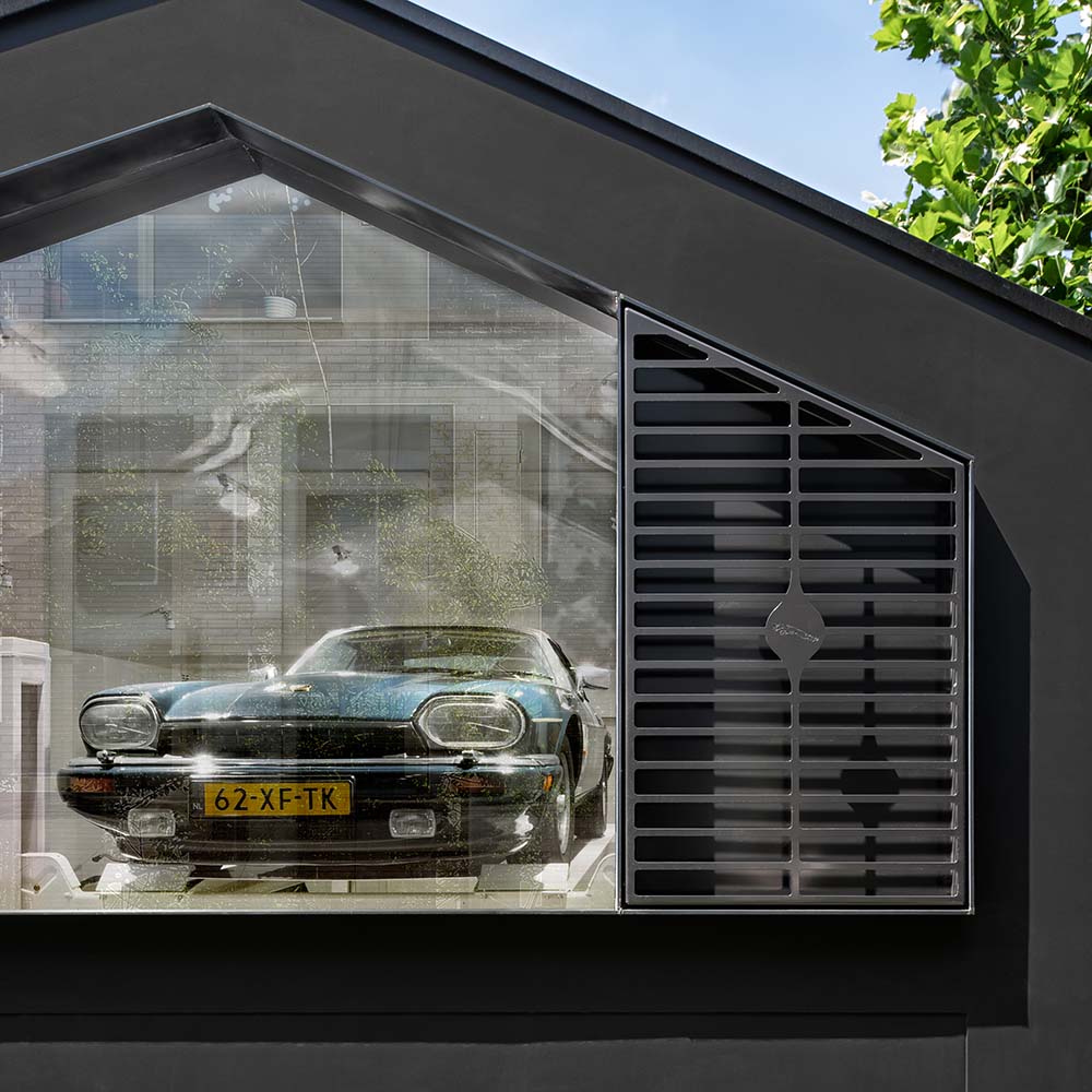 This is a close look at the house's garage with a glass wall and a car inside.
