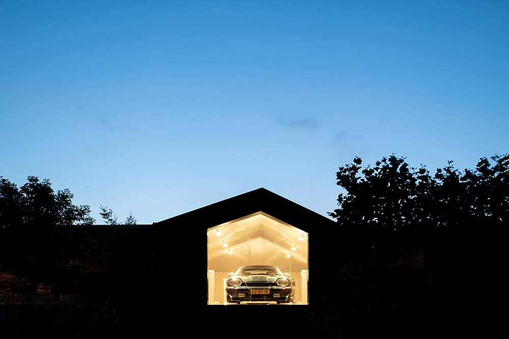 This is a nighttime view of the garage showcasing the warm glow of the interior that escapes through the glass wall.