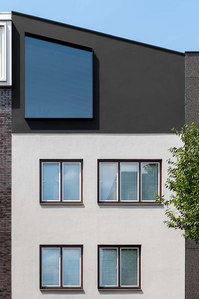 This is a close look at the upper floors of the front of the house with a modern design to its white and dark gray façade.