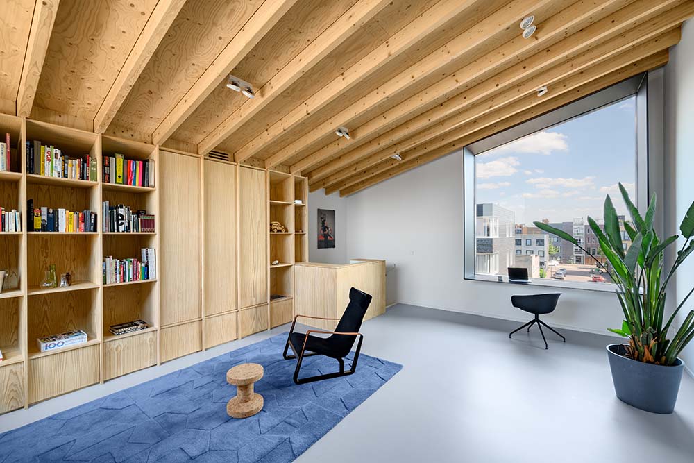 The built-in wooden structure of the bookshelves blend well with the exposed beams of the low shed ceiling.