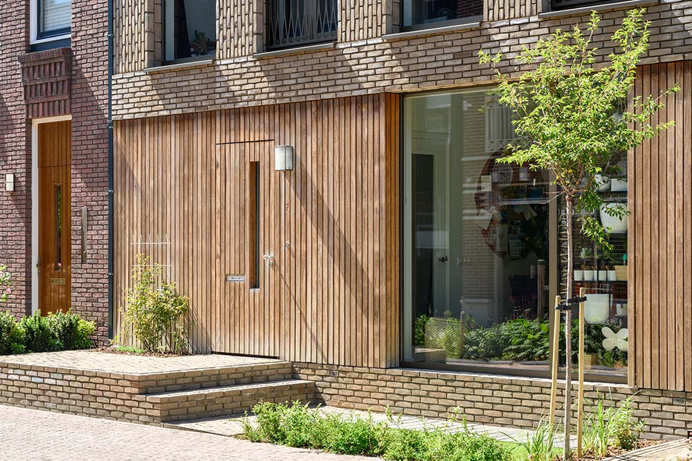 This is a close look at the front of the house with wooden slat panels at the main entrance and terracotta bricks.