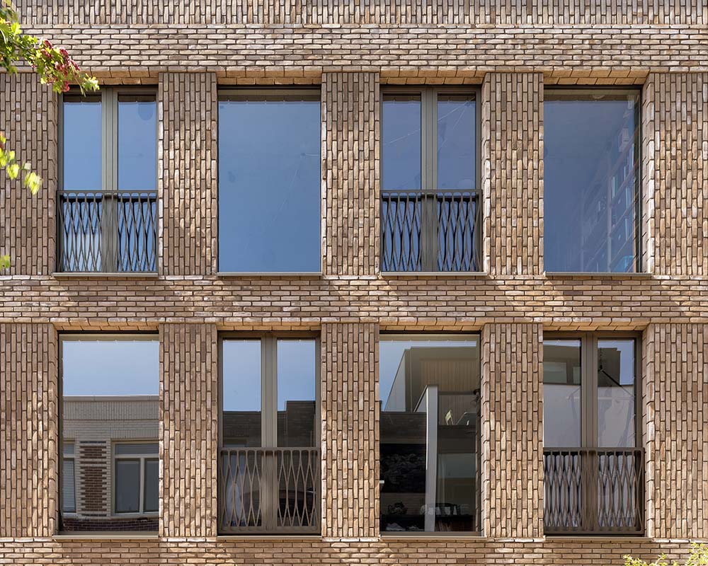 This is a close look at the upper floors of the house with terracotta bricks and glass windows.