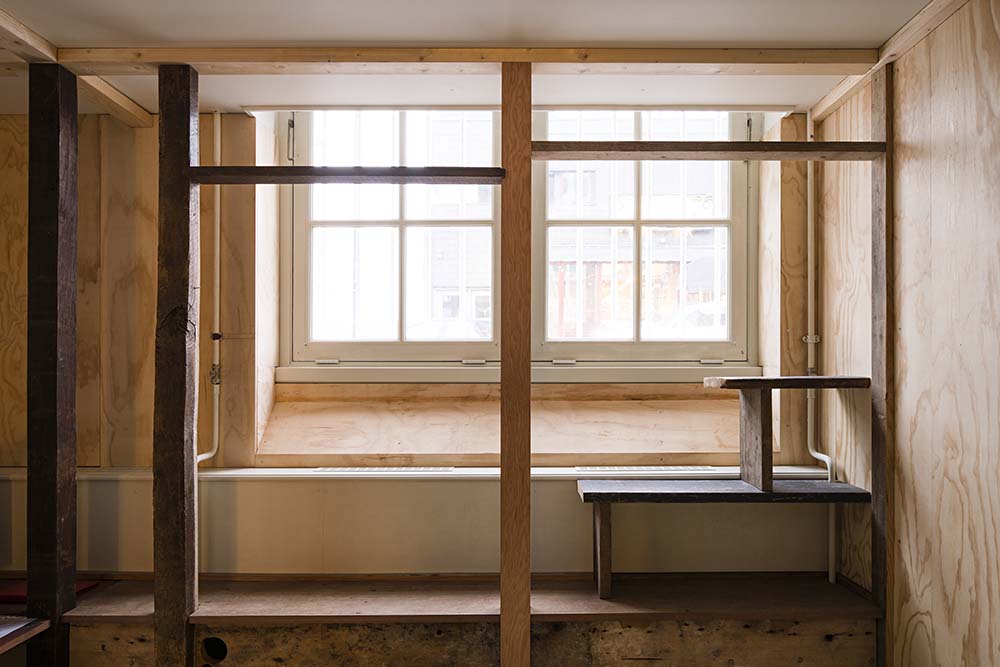 This is a close look at the other window with a built-in wooden bench and wooden shelves on the side.