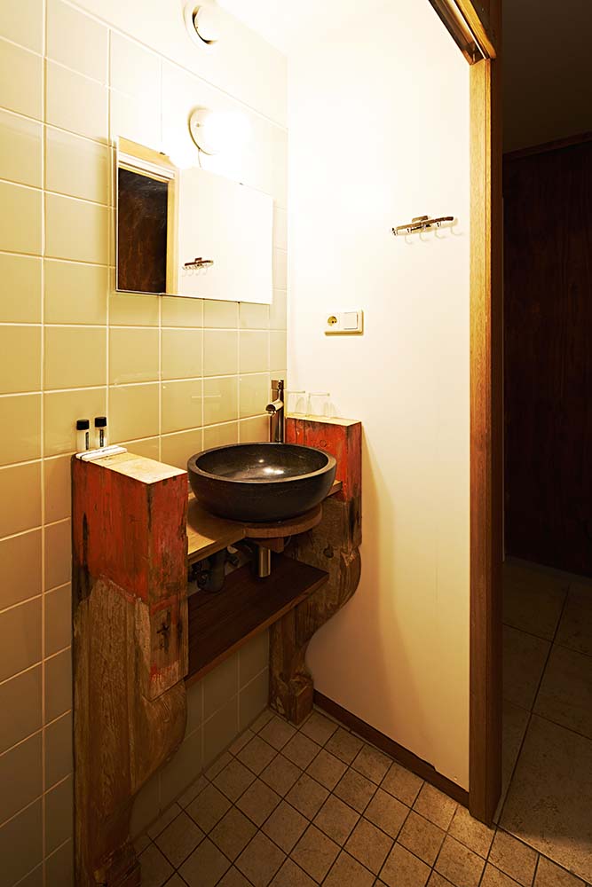 The bathroom has a rustic wooden vanity structure that stands out against the beige subway tiles.