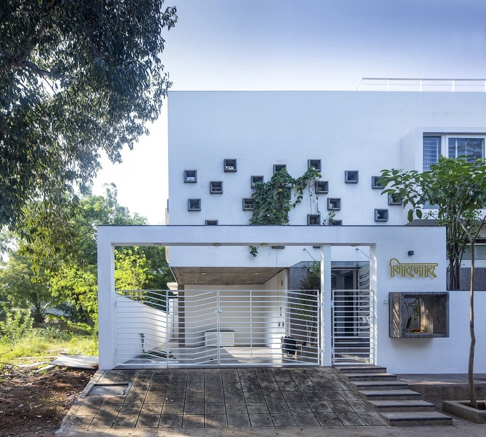 This is a close look at the front of the house with white structures, a white wrought iron gate and small windows.