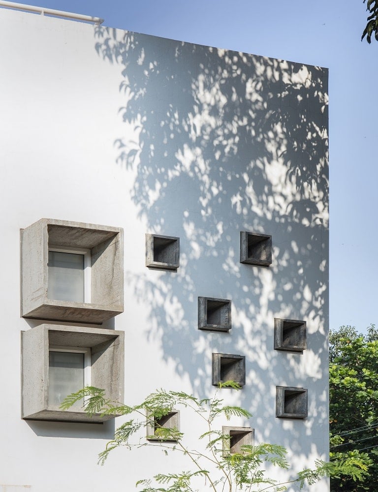 This is a close look at the exterior corner of the house with small concrete windows that stand out against the white exterior walls.