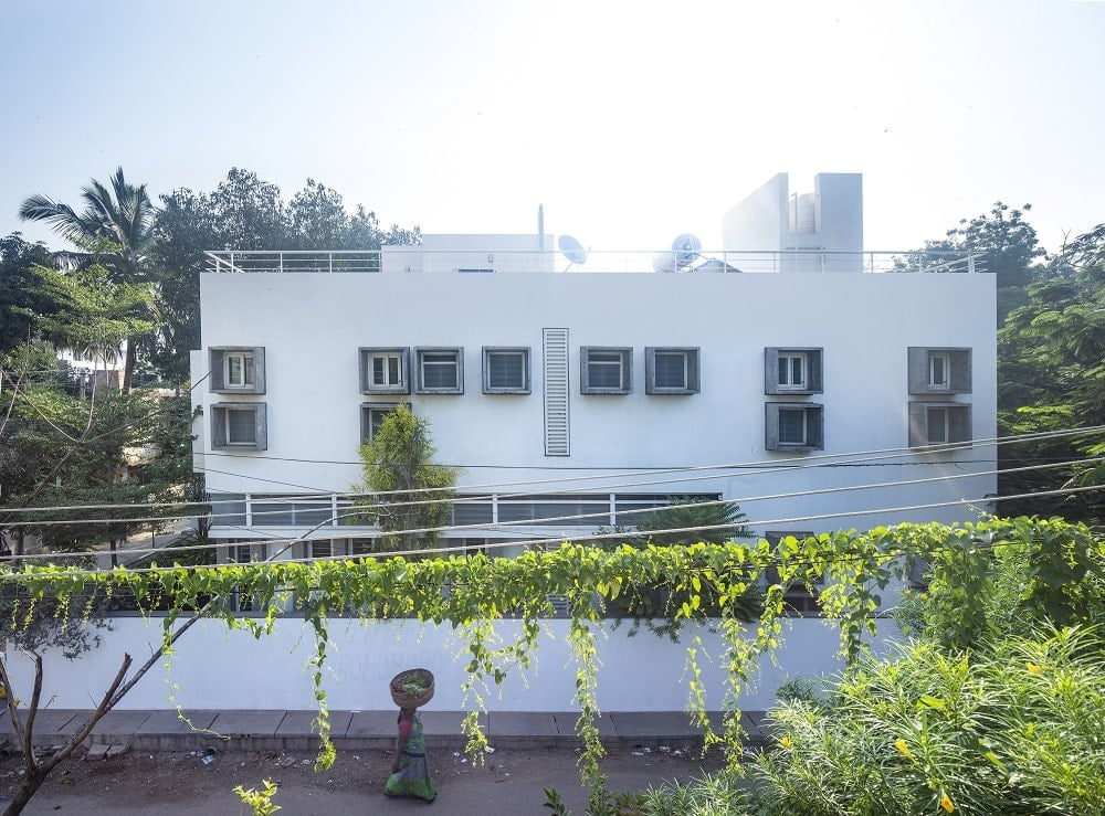 This view of the house shows a tall concrete fence on the outer area and a rooftop area above.