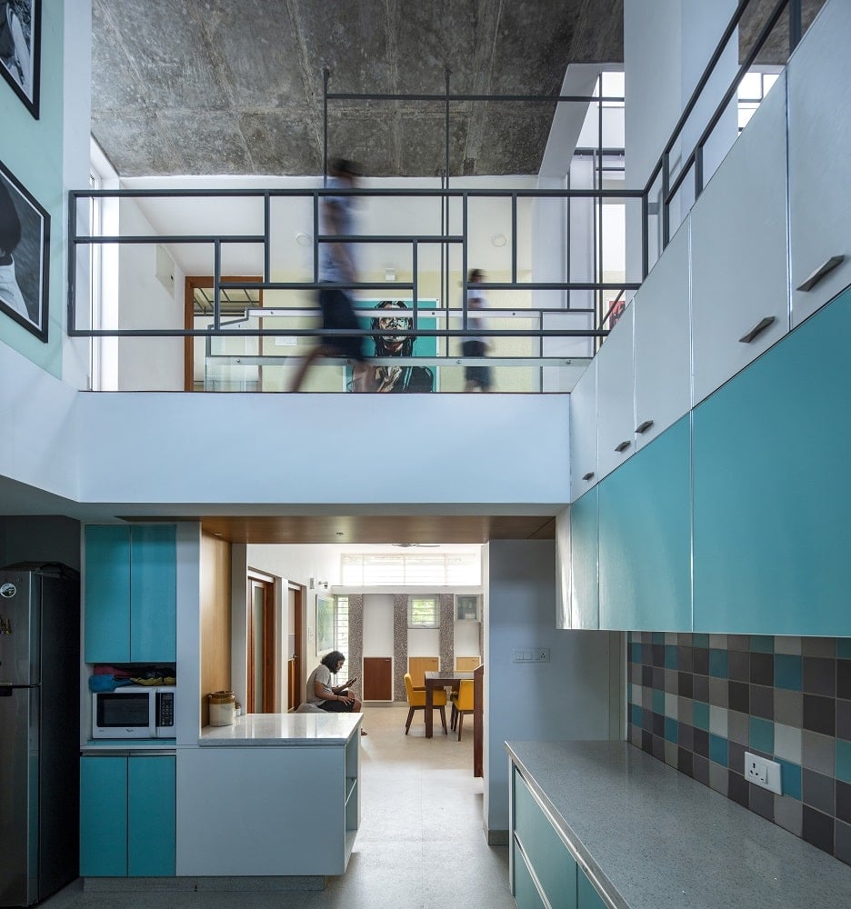 The kitchen has a tall ceiling with an indoor balcony that has wrought iron railings.