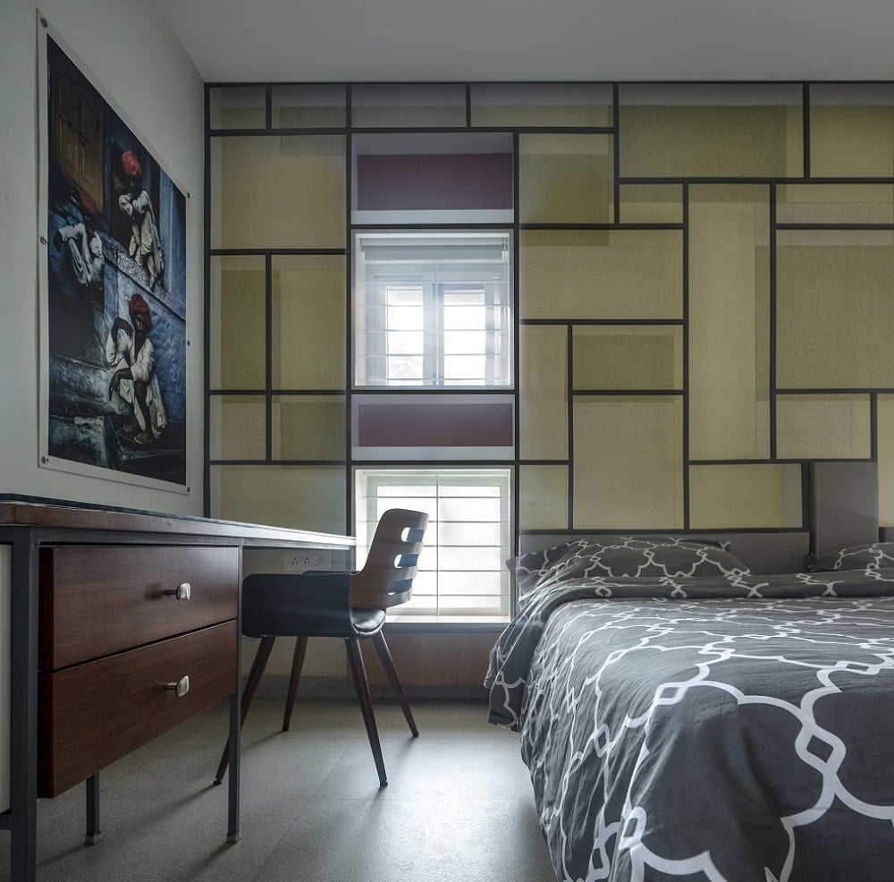 This is a close look at the bedroom that has a patterned sheet on its bed complemented by the geometric patterns of the wall behind the headboard.