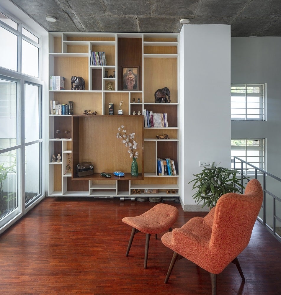 This is a closer looka t the reading area n the side of the indoor garden with a lounge chair by the built-in bookshelves.