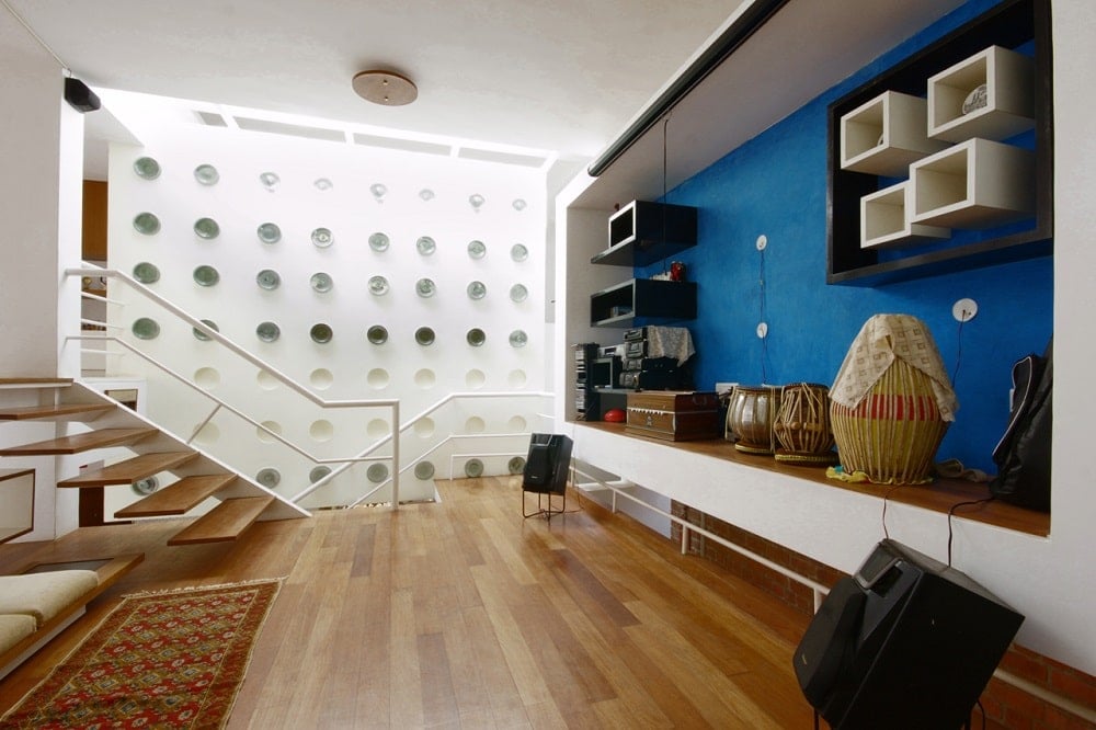 This is a close look at one of the landings of the house with a large entertainment cabinet built into the wall on one side across from the comfortable seating area with a colorful area rug and hardwood flooring.
