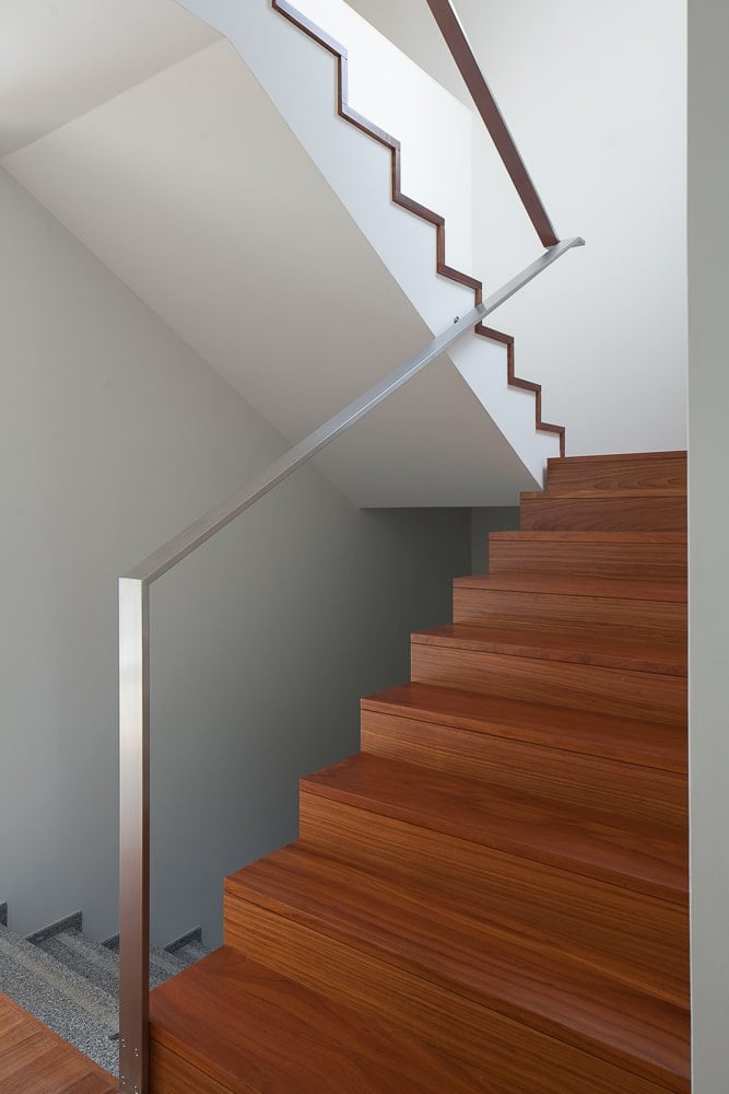 This is a close look at the staircase with sets of wooden steps that stand out against the bright beige walls.