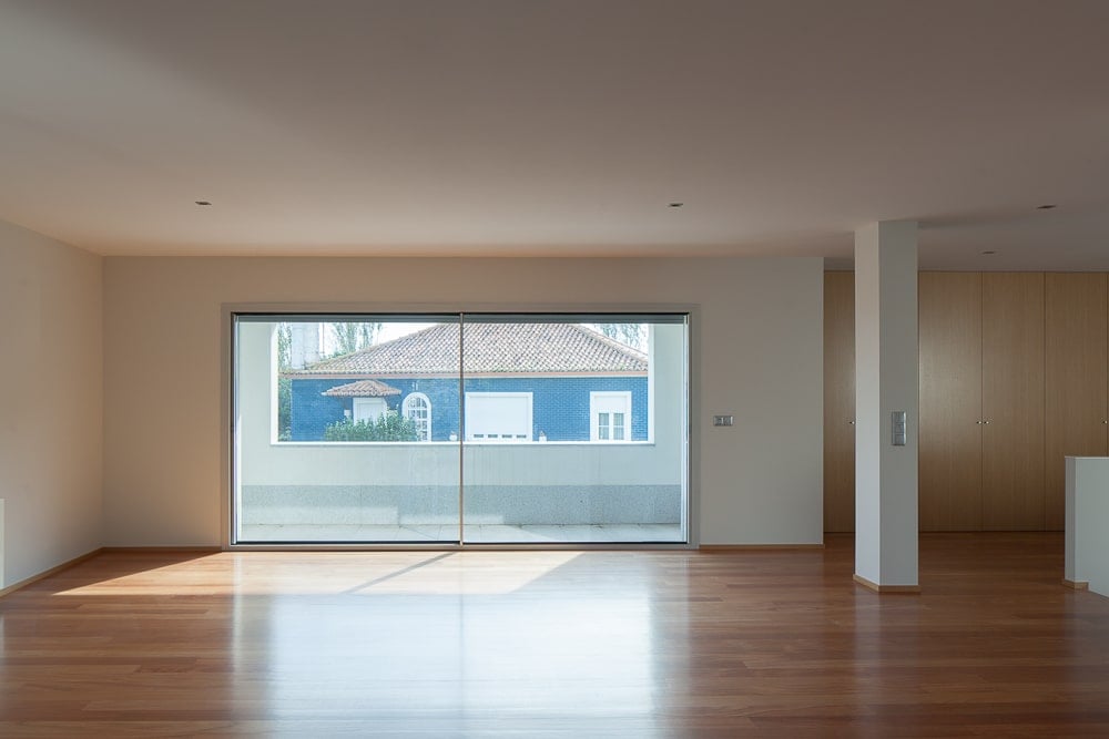 This is an interior view of the great room of the house with a spacious hardwood flooring paired with beige walls, glass doors and beige ceiling.