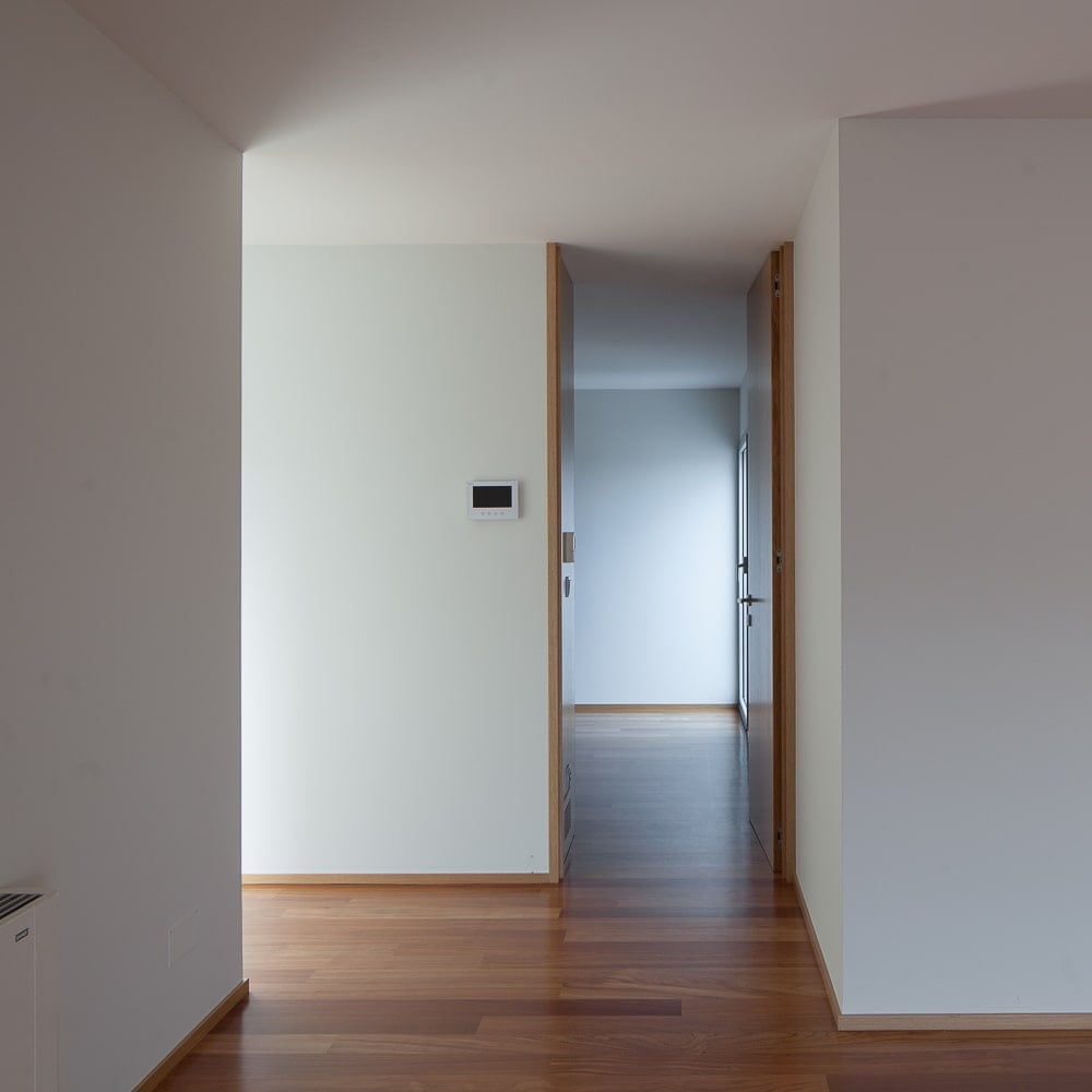 This is an upper floor hallway with bright beige walls and ceiling complemented by the hardwood flooring.