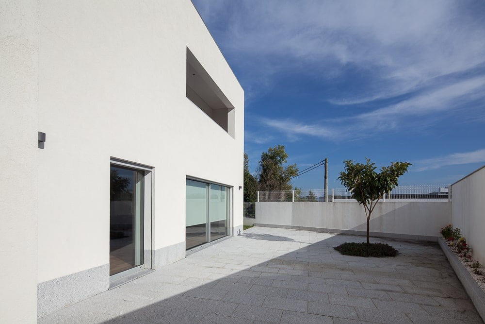 This is the outdoor area just after the glass doors of the living room area with concrete flooring and a planter with a tree.