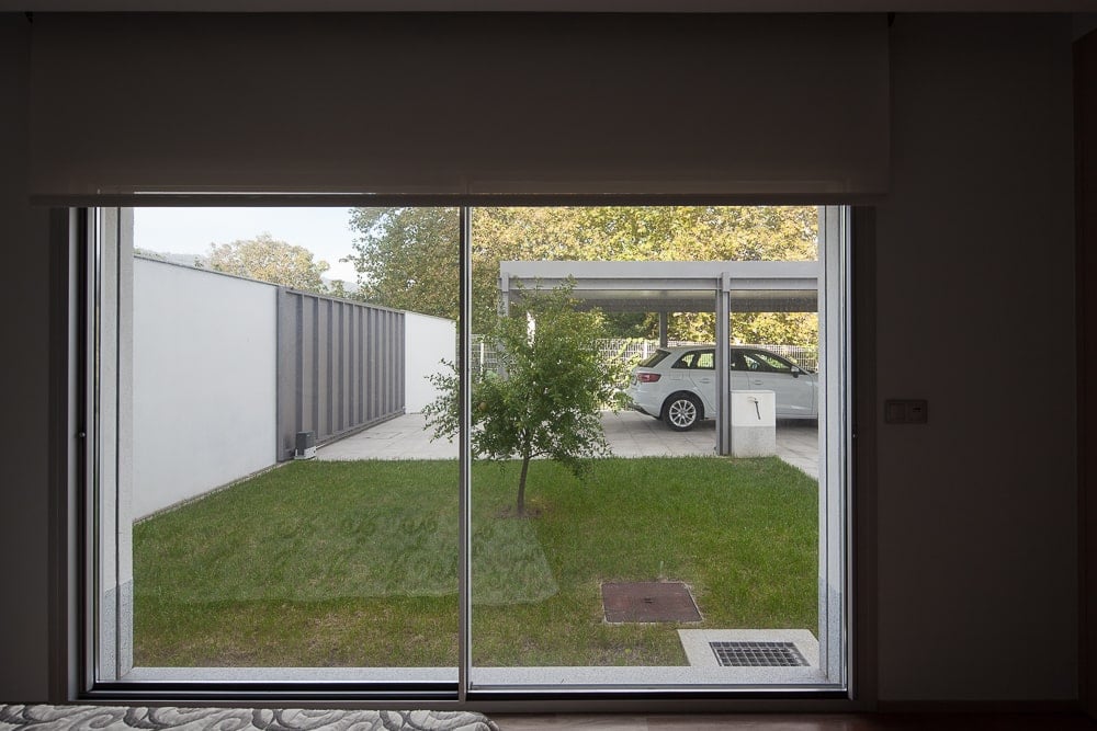 This is a view of the glass wall out onto the grass lawn garden and the garage car port beyond the lawn.