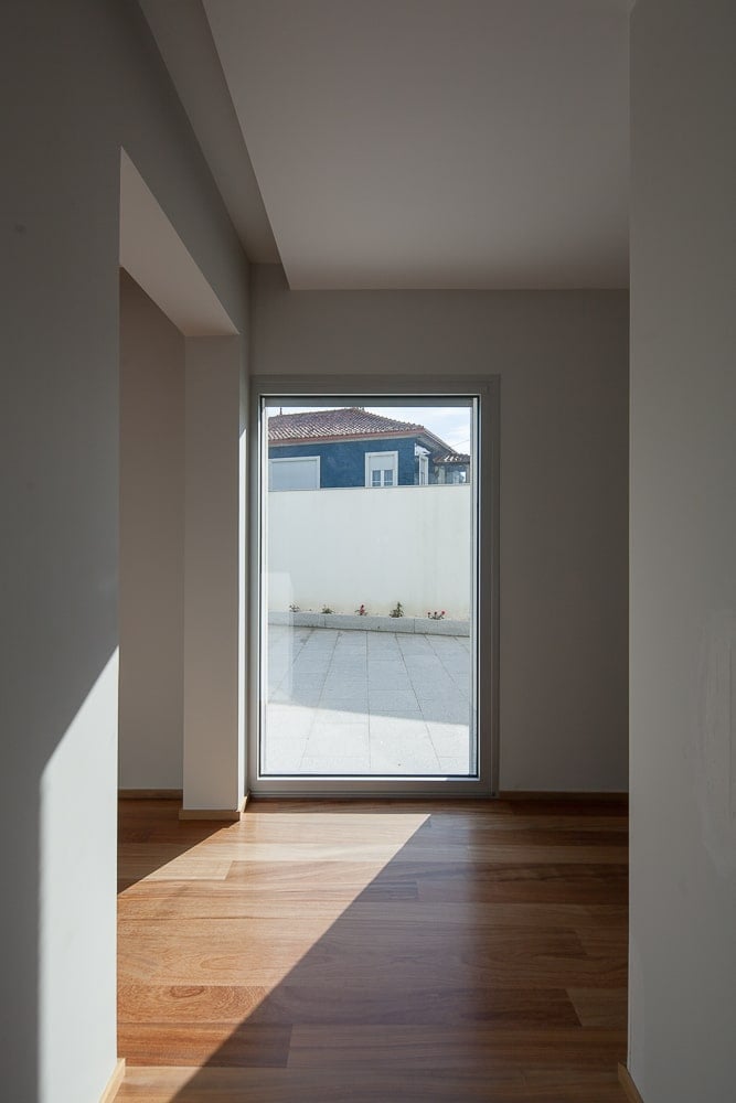 This is an interior hallway of the house leading to the glass door on the far side that leads to the outdoor areas of the house.