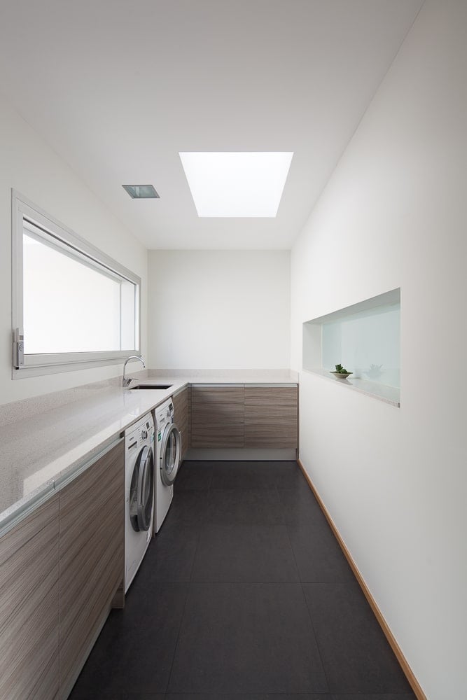 This is the laundry room with a couple of laundry machines built into the L-shaped cabinetry lining the walls.