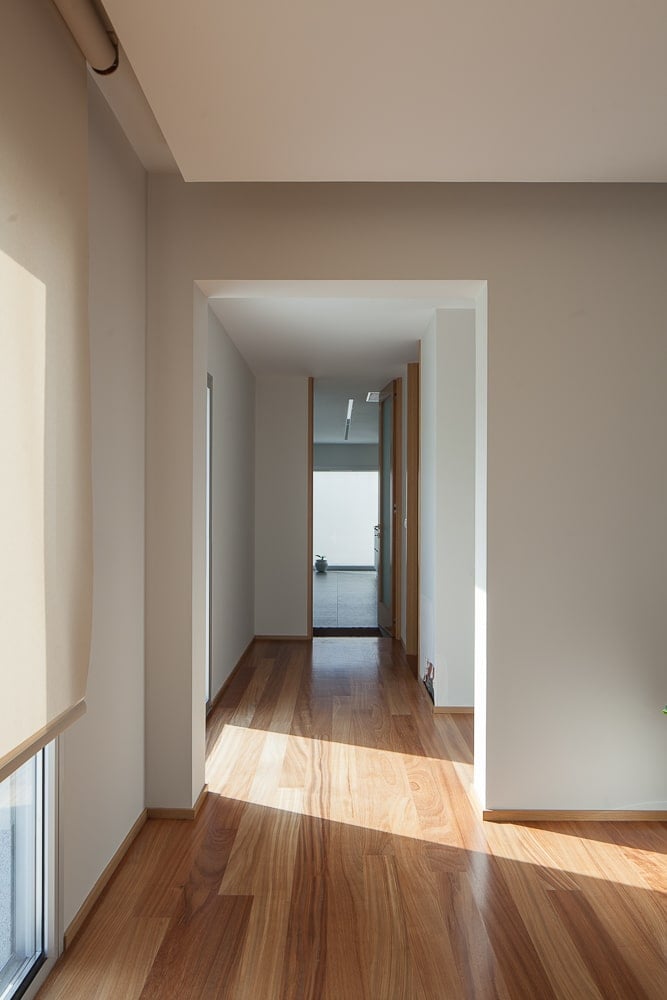 This is a close look at a hallway within the house with hardwood flooring that paired well with the bright beige walls and ceiling.