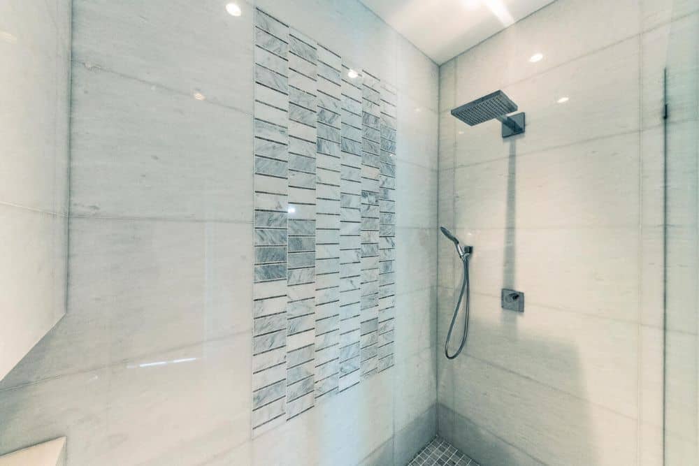 This is a close look at the shower area of the bathroom with beige tiles on the walls that make the fixtures stand out.