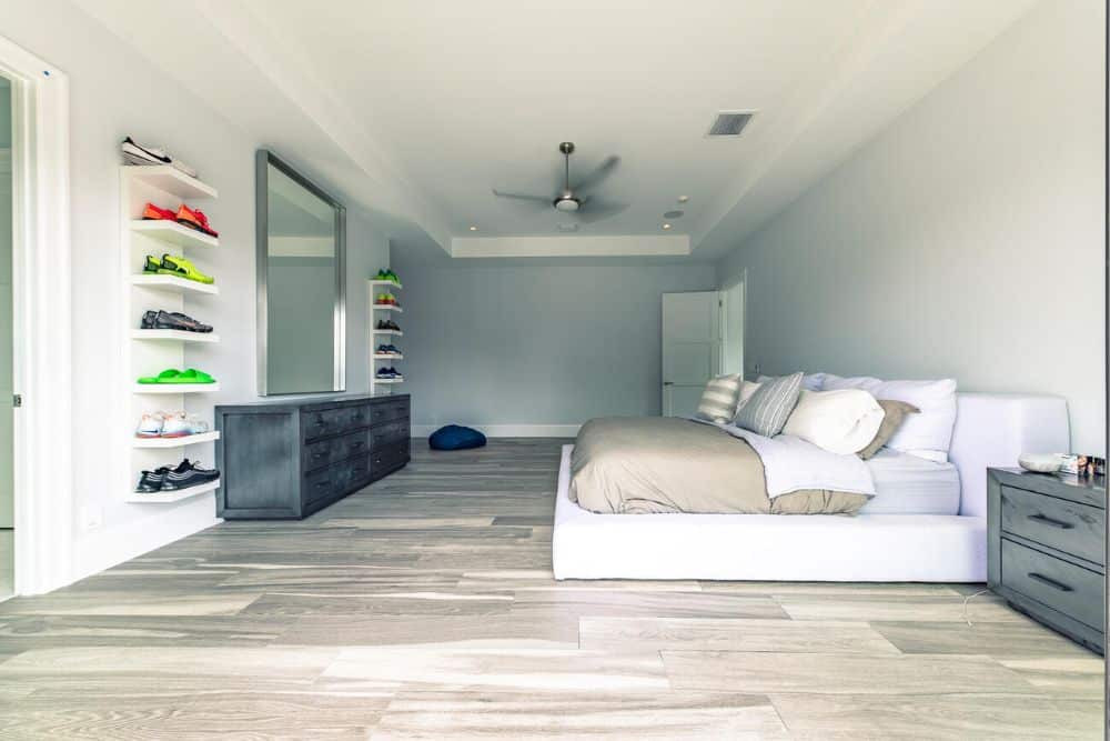 The primary bedroom has a large white platform bed across from the large gray dress topped with a large wall-mounted mirror.