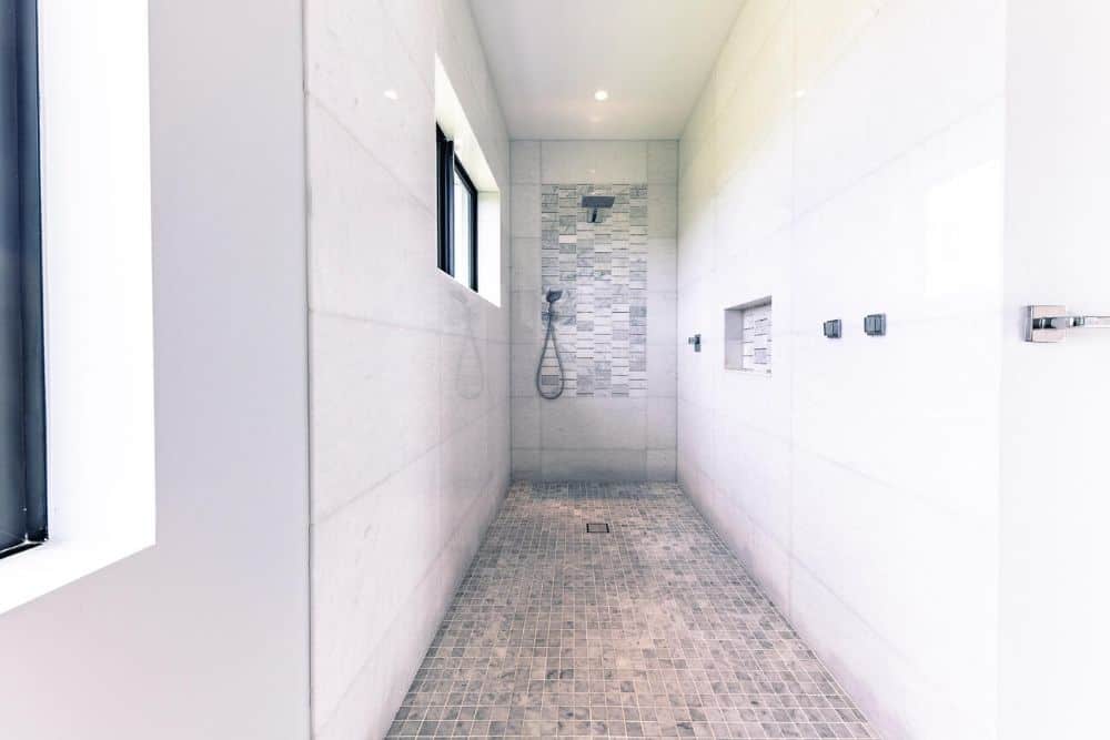 This is the other shower area with patterned gray tiles on the floor matching the backsplash of the shower area that has a built-in alcove on its wall.